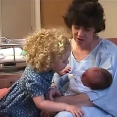 Мало девојче го смирува своето новородено братче да не плаче