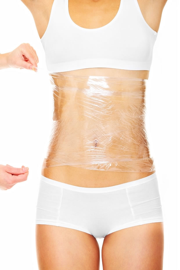 A picture of a sexy female body being wrapped around with foil to reduce fat over white background