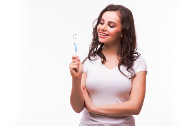 Beautiful woman with teeth braces, cleans teeth with toothbrush
