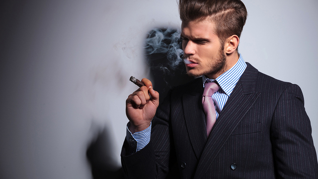 side view of a fashion model in suit and tie enjoying his cigar