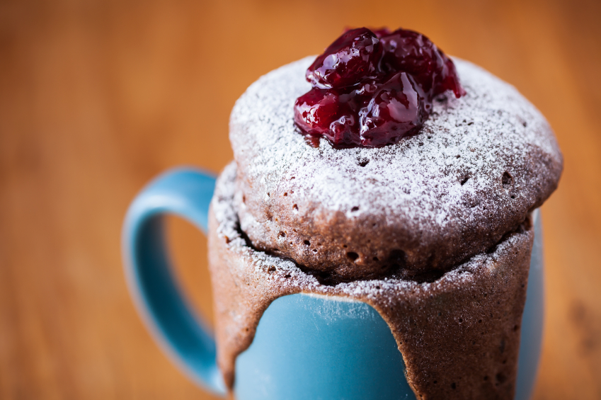 Warm chocolate cake in a mug sprinkled with icing sugar and fres