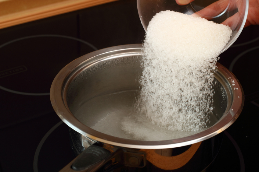 Pouring sugar into saucepan with boiling water