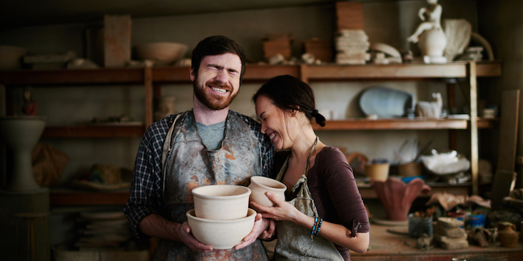 Happy potters family posing in small workshop