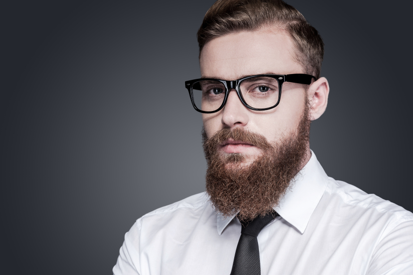 Portrait of confidence and creativity. Handsome young bearded man in shirt and tie looking at camera while standing against grey background