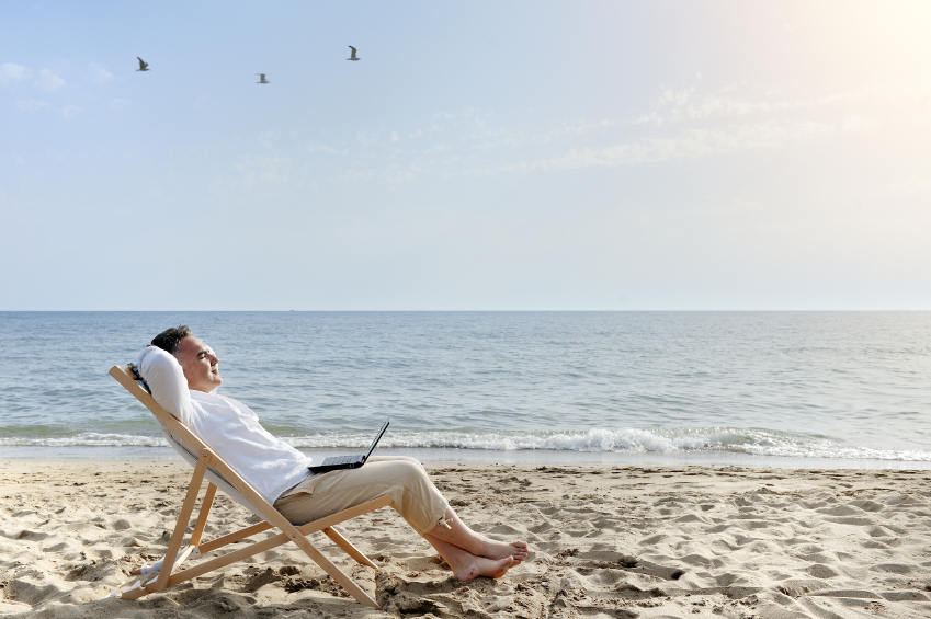 man with laptop computer relaxing on the beach