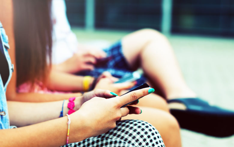 Hands of three messaging teenagers