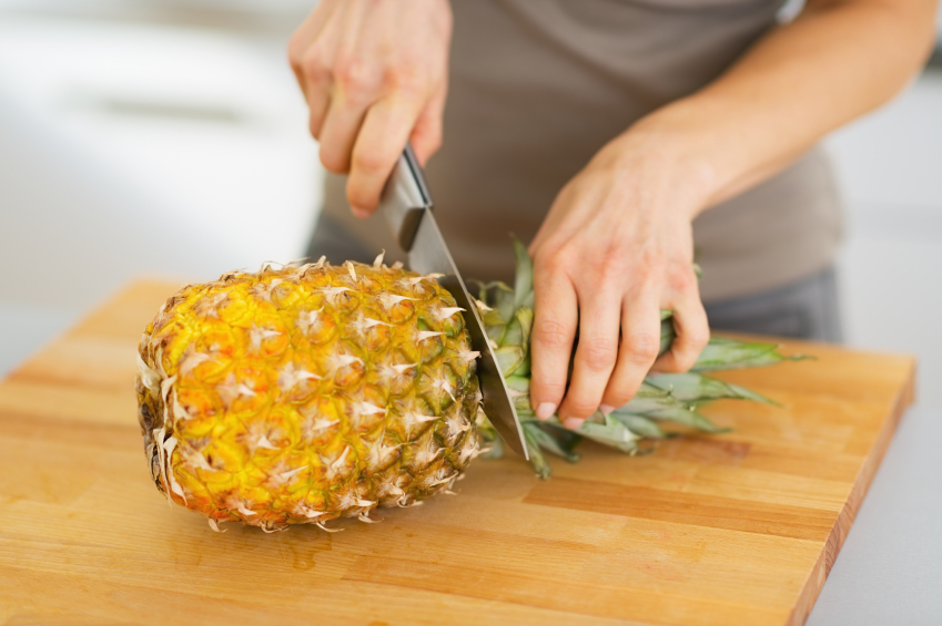 Closeup on woman cutting pineapple