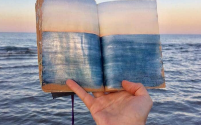 Артистка скицира морски пејзажи кои потоа ги фотографира држејќи ги над крајбрежјето