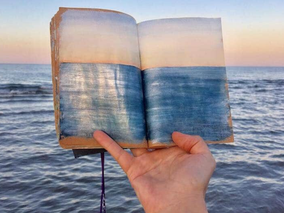 Артистка скицира морски пејзажи кои потоа ги фотографира држејќи ги над крајбрежјето